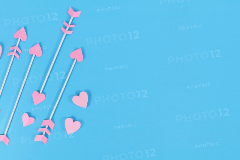 Pink cupid's arrows with heart shaped tips on blue background with copy space
