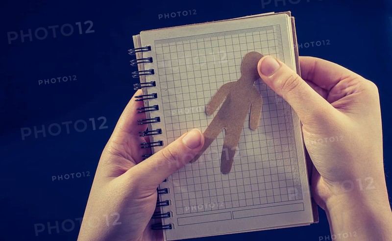 Man shape cut out of paper in notebbok in hand