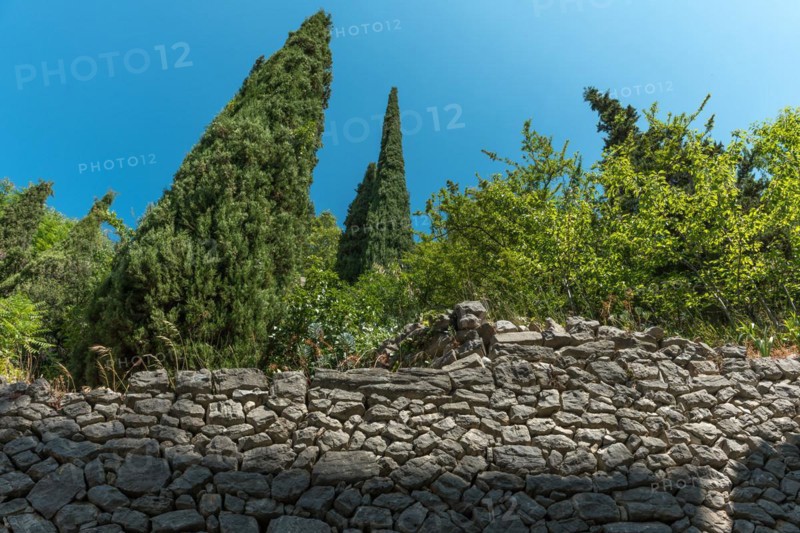 Old stone wall between Provencal garden and path in a typical village of Provence. Montbrun-les-Bains