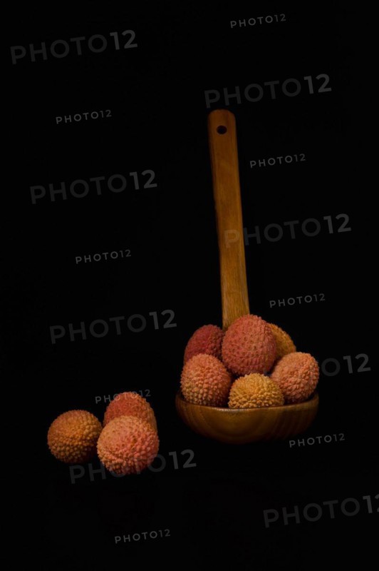 Fresh lychees in a wooden spoon isolated on a black background