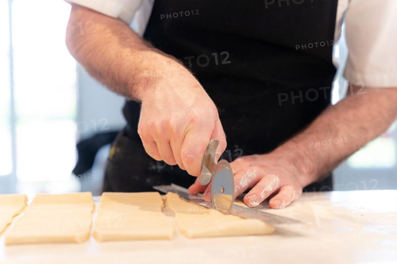 Detail of the hands of a man baking croissants