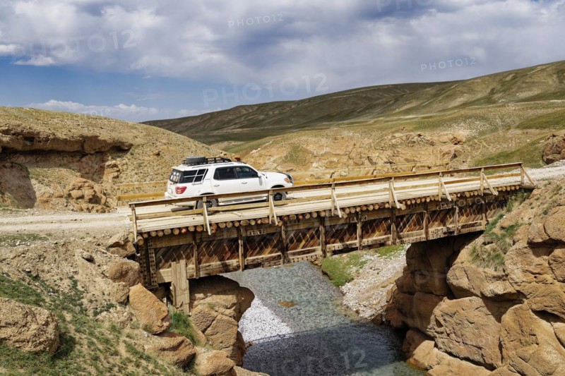 Four-wheel drive car crossing a wooden bridge over a wild gorge