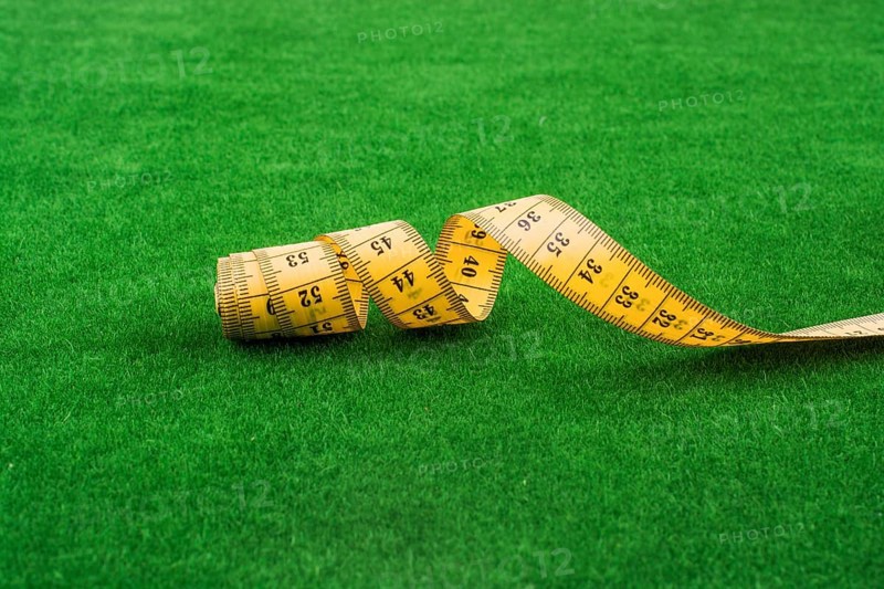 Yellow color measuring tape on green grass