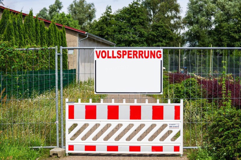A closed path with a barrier and a construction fence with a rectangular board with a lot of text space with the word FULL CLOSURE