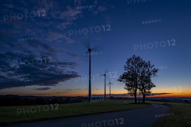 Three wind turbines with road at blue hour