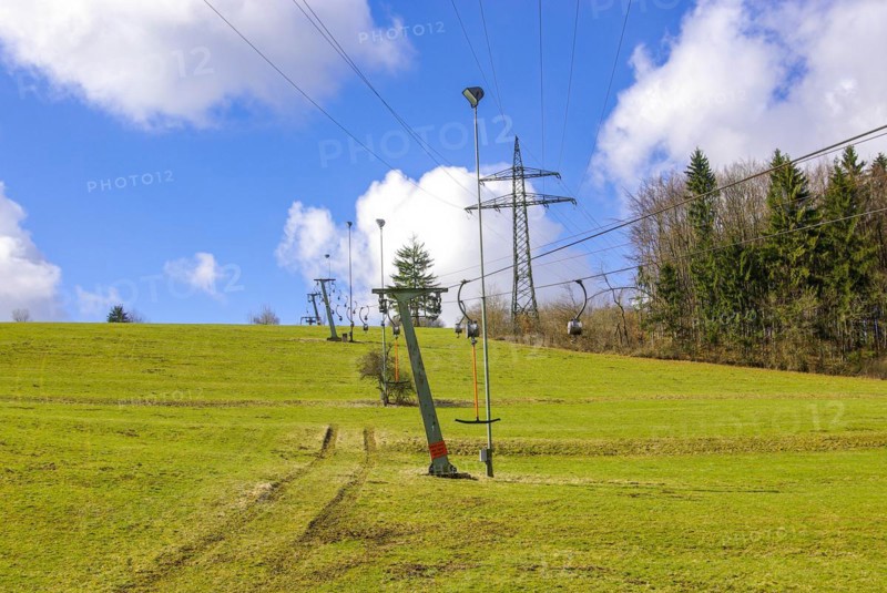 Ski lift at standstill due to lack of snow caused by climate change at the end of winter on a hill in Muensingen