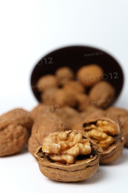 Walnuts in a brown bowl isolated on a white background