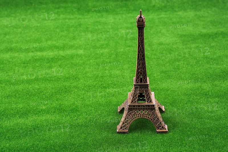 Little model Eiffel Tower on fake green grass field