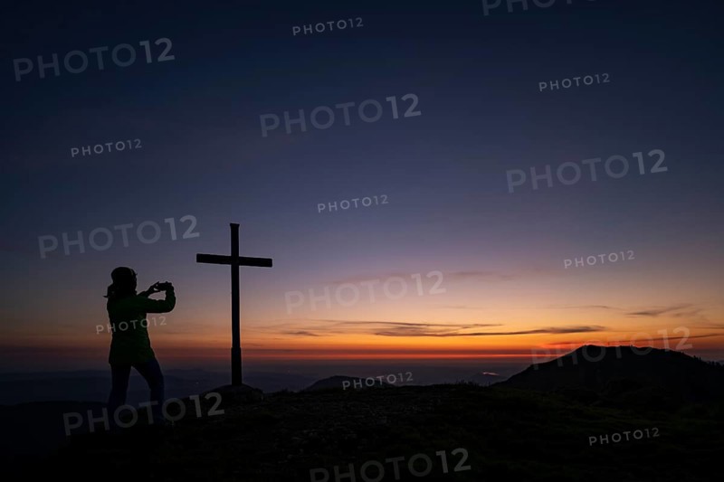 Mountaineer with mobile phone and sunrise in the background
