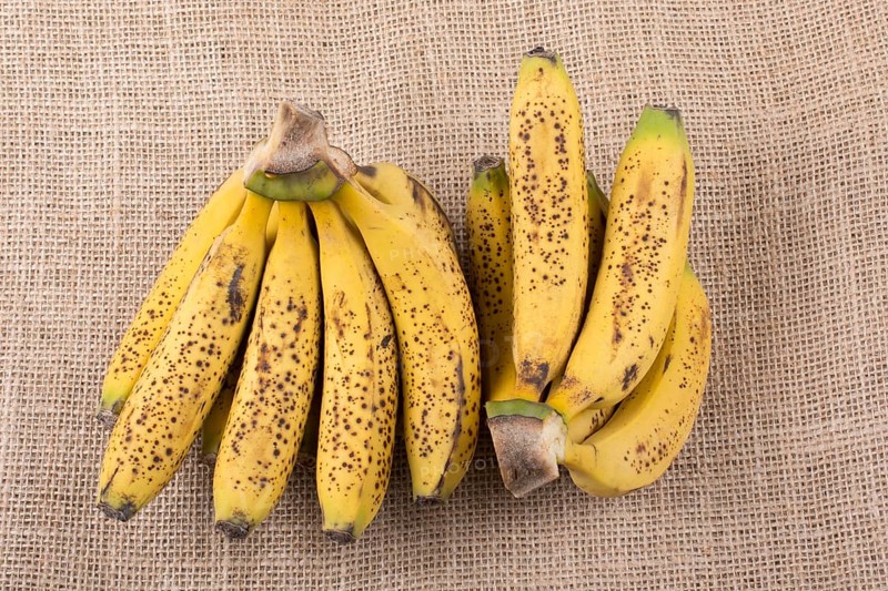 Bunch of yellow freckled bananas on a canvas texture
