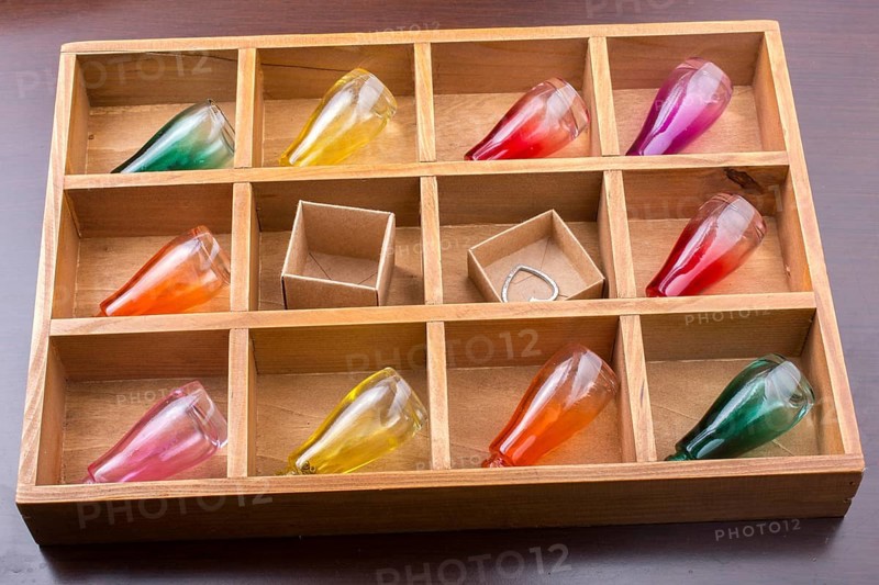Colorful small bottles and small carton boxes in a wooden box in the view