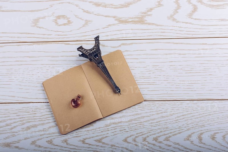 Eiffel tower miniature and a potion bottle on a brown notebook on a wooden background