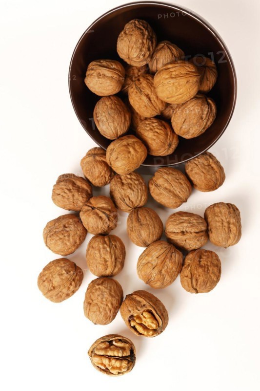 Walnuts in a brown bowl isolated on a white background