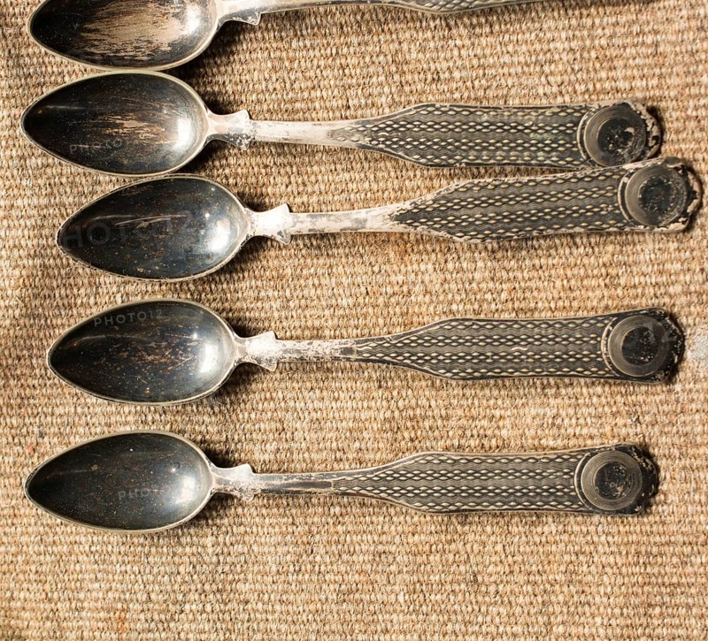 Stylish steel teaspoons on a textured background in display