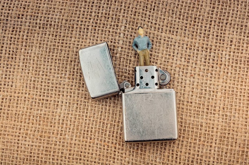 Man figurine in the chimney of a lighter on a textured as background