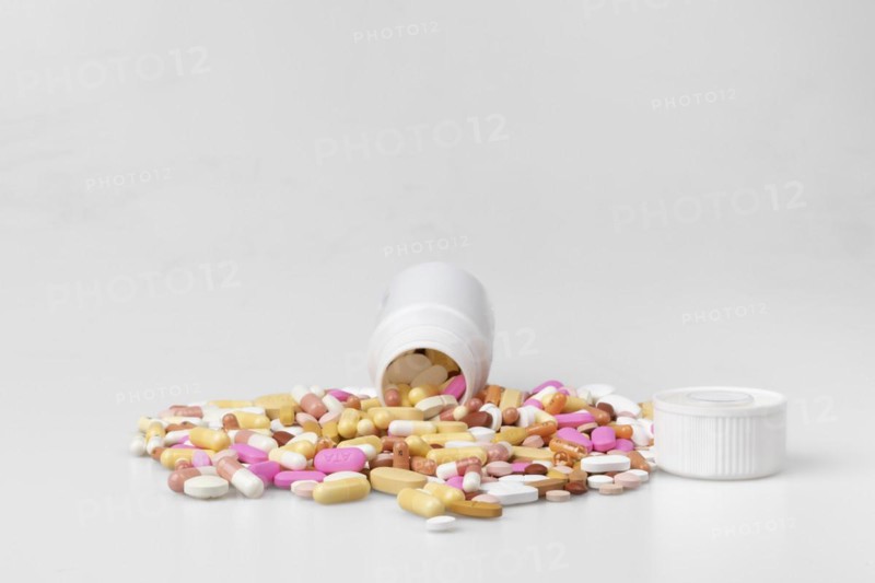 Coloured pills and capsules trickle out of plastic