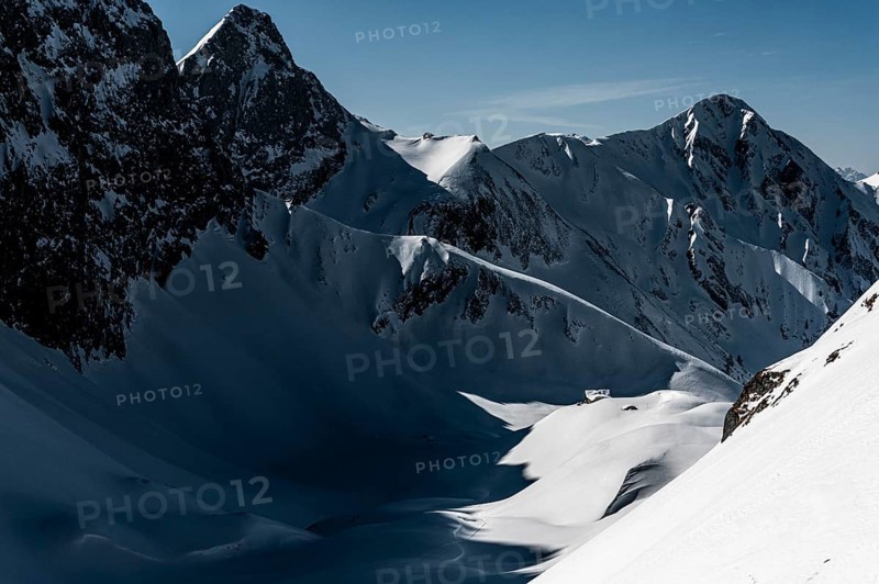 Mountain hut in deep snowy mountain landscape with light and shadow