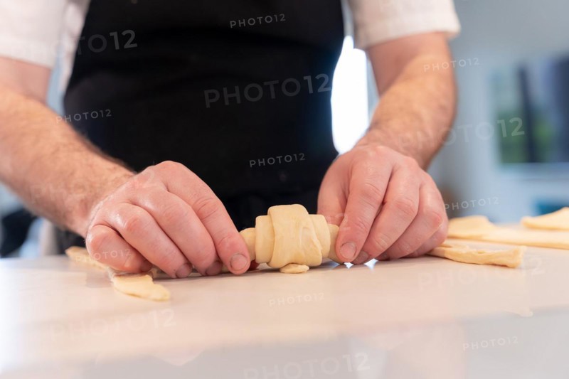 Hands of a man baking small croissants at home