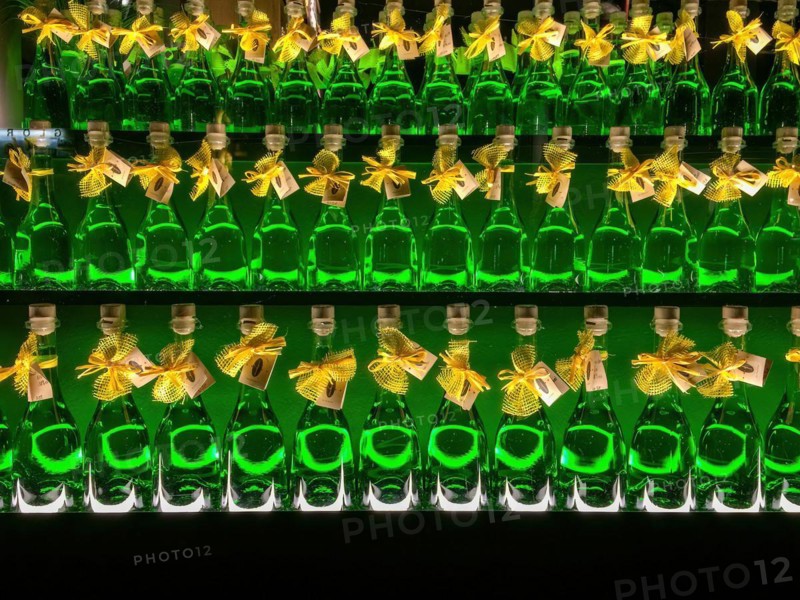 Three rows of bottles with alcoholic high-proof drink green absinthe