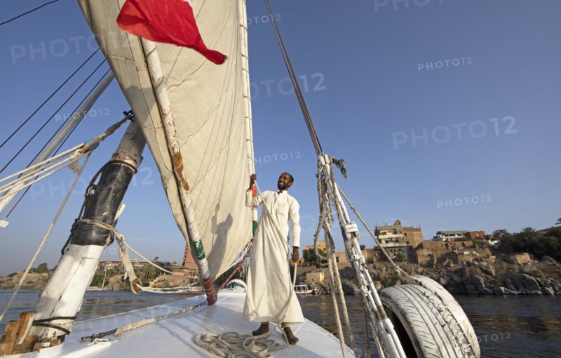 Egyptian man in traditional boatmens garb on a felucca or traditional sailing boat on the Nile