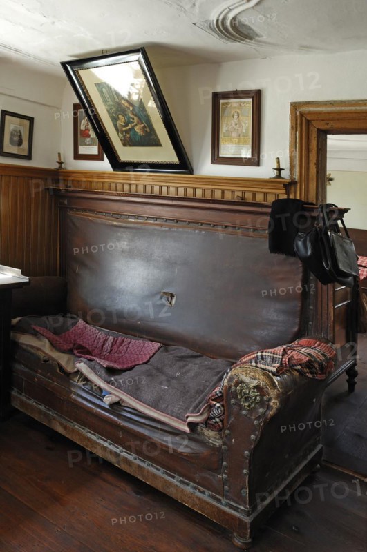 Sofa with saints border in the living room with a view into the sleeping chamber