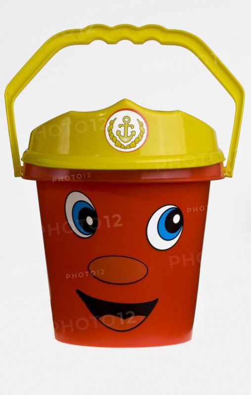 A bright red plastic childs bucket with a yellow handle and a smiley face