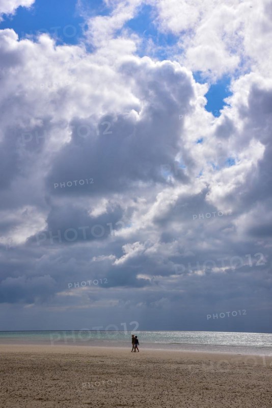 A couple taking a walk on the beach at low tide