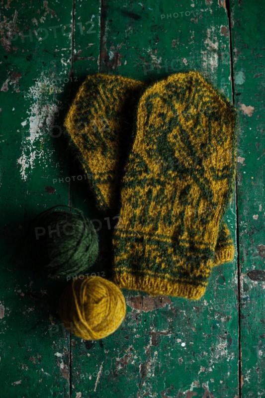 Hand-knitted gloves with pattern next to ball of wool