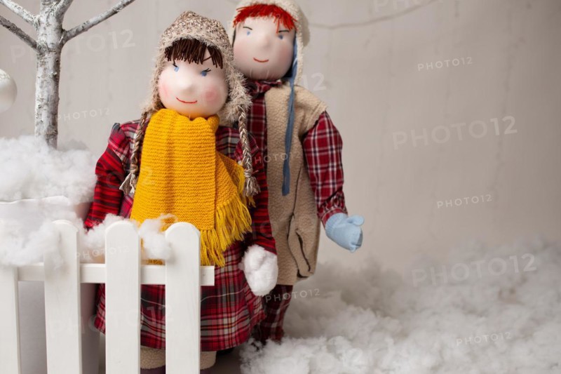 Two plush children standing by the fence in a Christmas arrangement