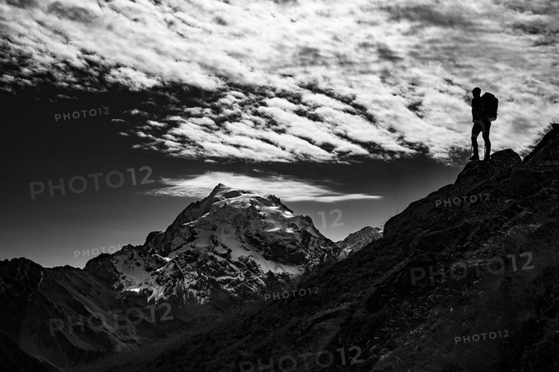 Mountaineer in backlight with cloudy sky in front of Ortler summit massif