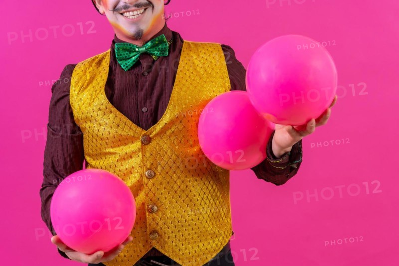 Clown with white facial makeup on a pink background