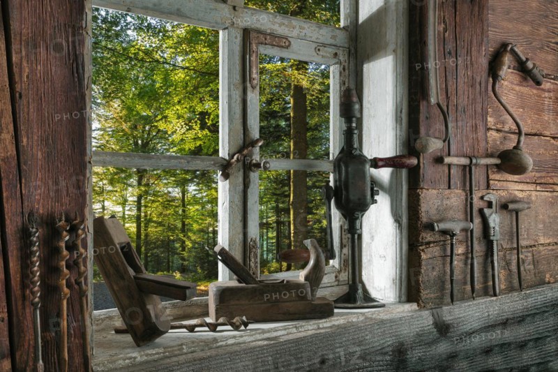 Rustic workshop with old tools and view out of the window into the forest