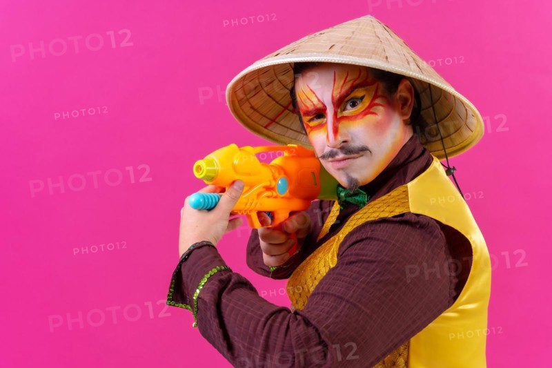 Clown with white facial makeup on a pink background