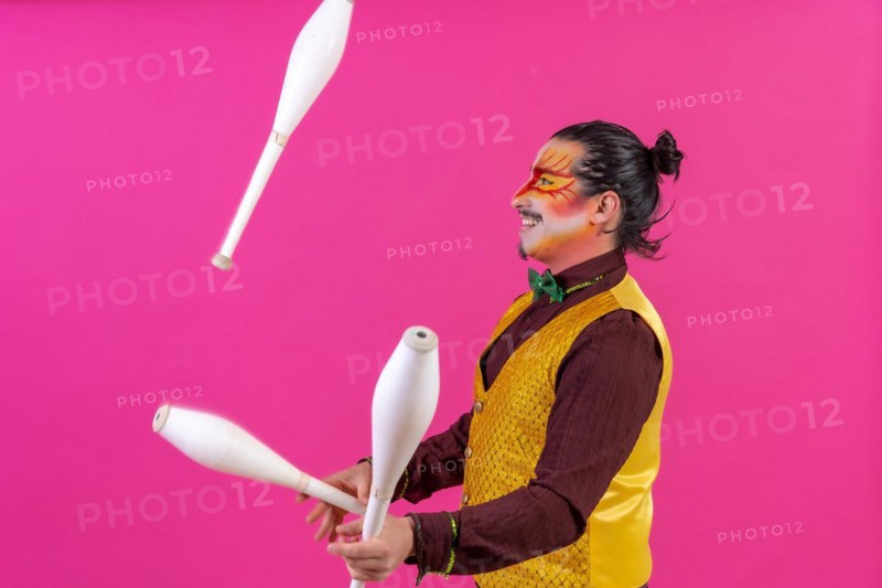 Clown with white facial makeup on a pink background
