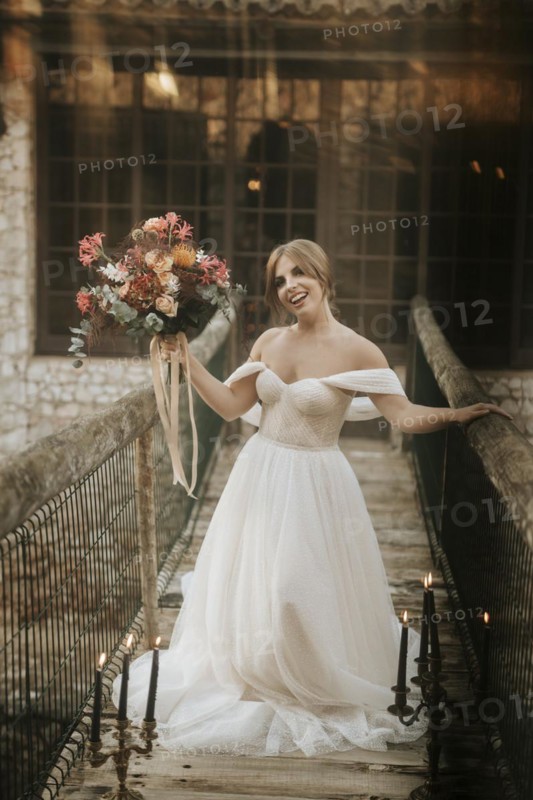 Beautiful rustic bride posing on wooden bridge full of candles