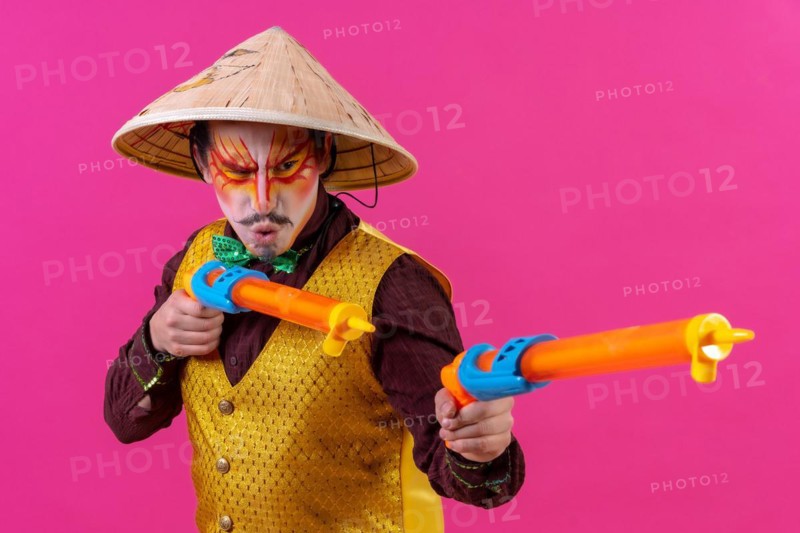 Clown with white facial makeup on a pink background