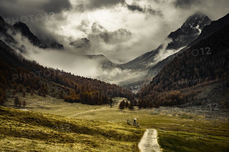 Way cross with path in autumnal mountain landscape with threatening cloudy sky