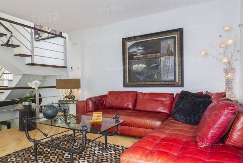 Red leather sectional sofa and black wrought iron with glass top coffee table in living room inside modern home
