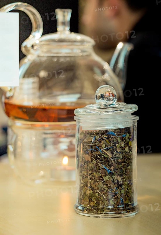 Herbal tea brewed in glass teapot and tea plant in a bottle