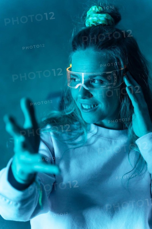 Woman with futuristic glasses gesturing against a blue background