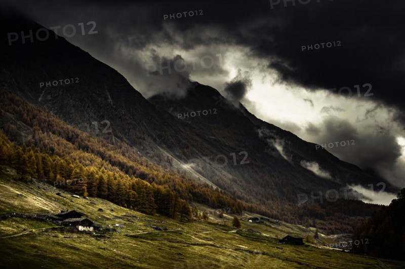 Alpine hut in autumnal mountain landscape with threatening cloudy sky