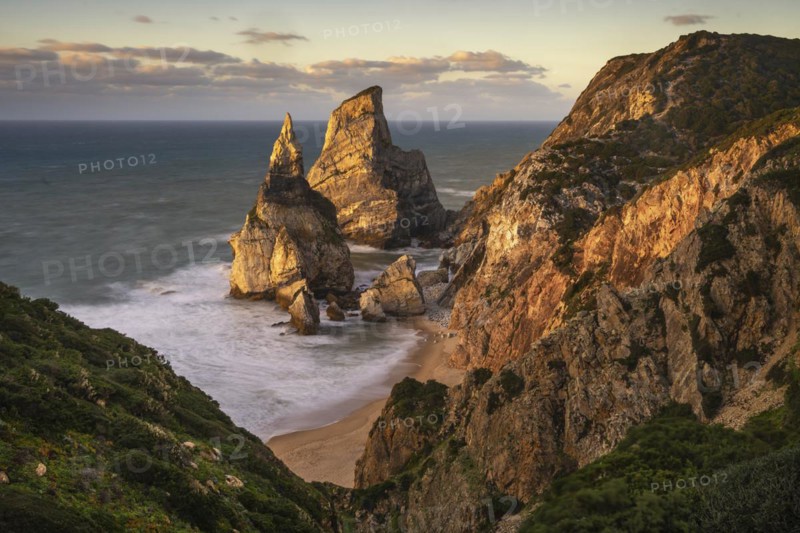 Sunset on sandy beach and cliff with rocks