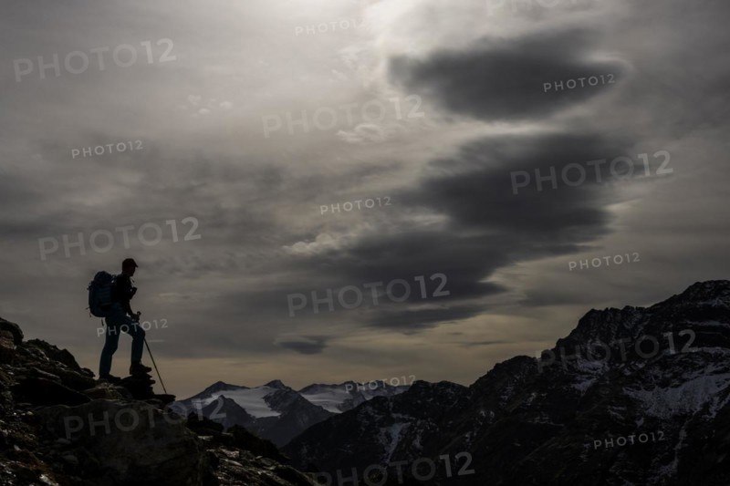 Climbers on rocks in backlight with cloudy sky in the background South Tyrolean mountains
