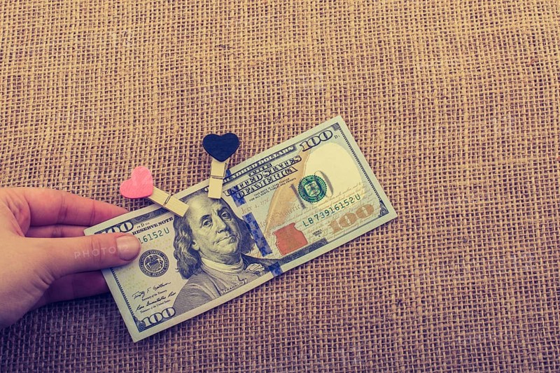 American 100 dollar banknotes with a heart clip on a string