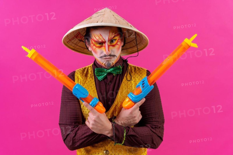 Clown with white facial makeup on a pink background