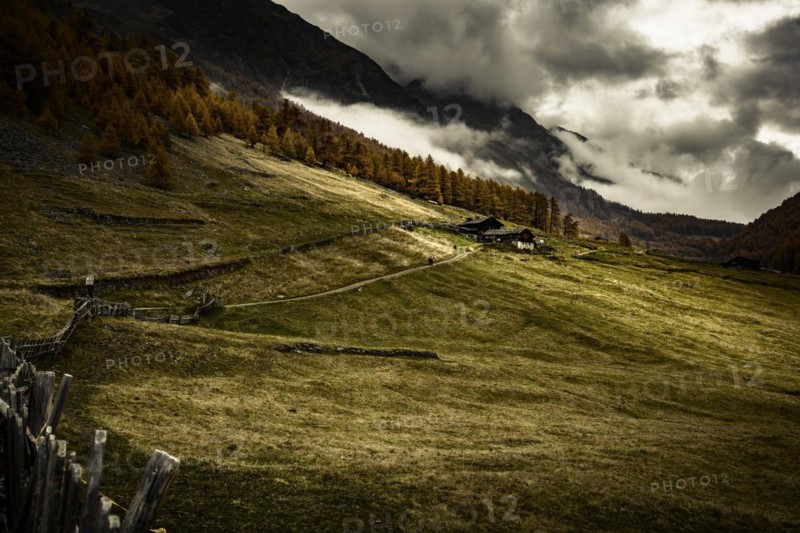 Alpine hut in autumnal mountain landscape with threatening cloudy sky