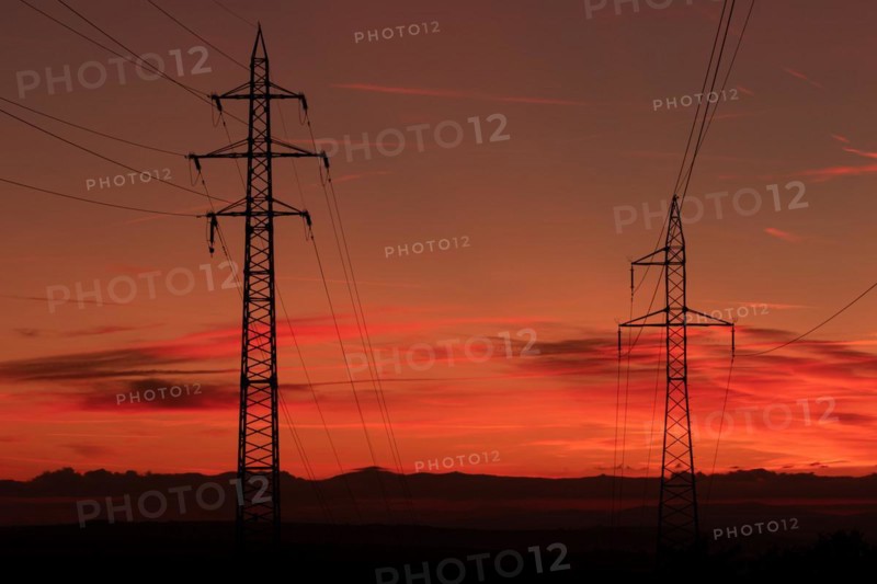 Silhouette of high voltage lines and transmission towers thru the Moravian field at sunrise