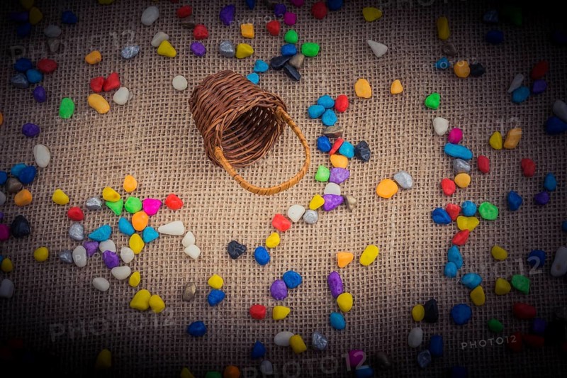 Basket and spilled pebbles on canvas background