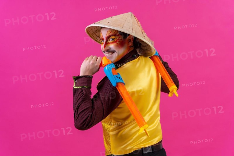 Portrait of a clown with white facial makeup on a pink background