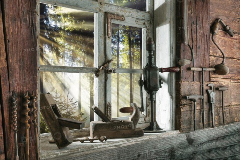 Rustic workshop with old tools and view out of the window into the forest